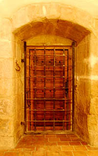 The kitchen door has a yett - a metal gate, similar in principle to a portcullis, except that it opens like a door. Photo from inside the room, with both yett and door closed.